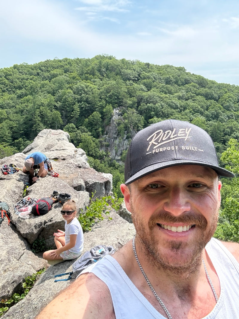 Black Ridley Original SnapBack with embroidered Ridley Purpose Built logo, worn at a rocky overlook